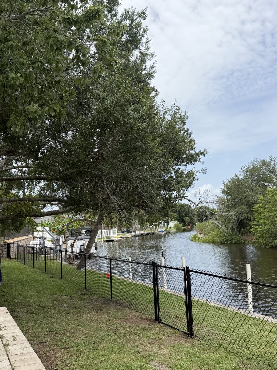 Black chain-link fence along a canal by Rodgers Services